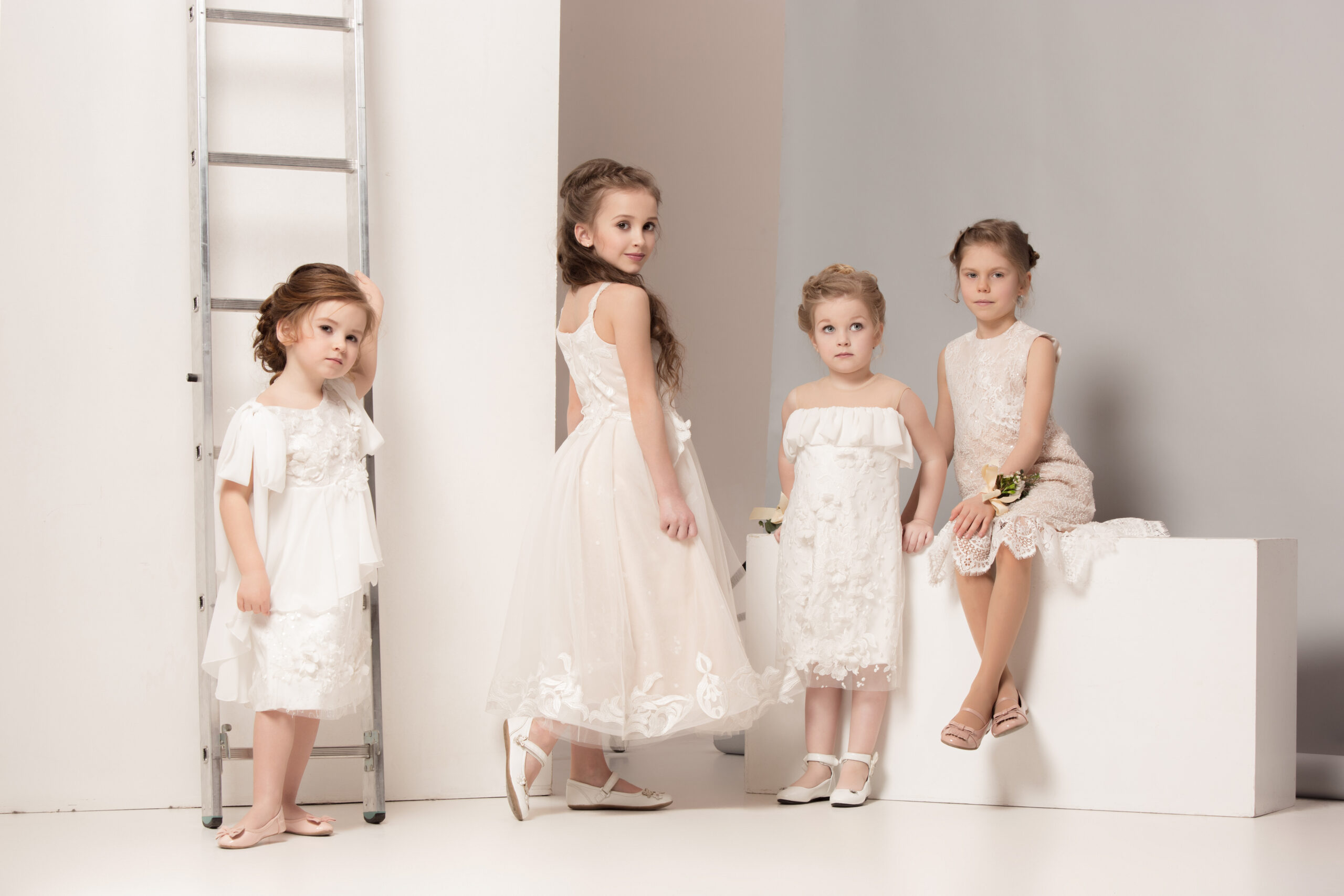 Little pretty girls with flowers dressed in wedding dresses. Lovely little girlfriends. girls dreaming of a wedding. Beauty, happiness, marriage, wedding style concepts. Studio shot