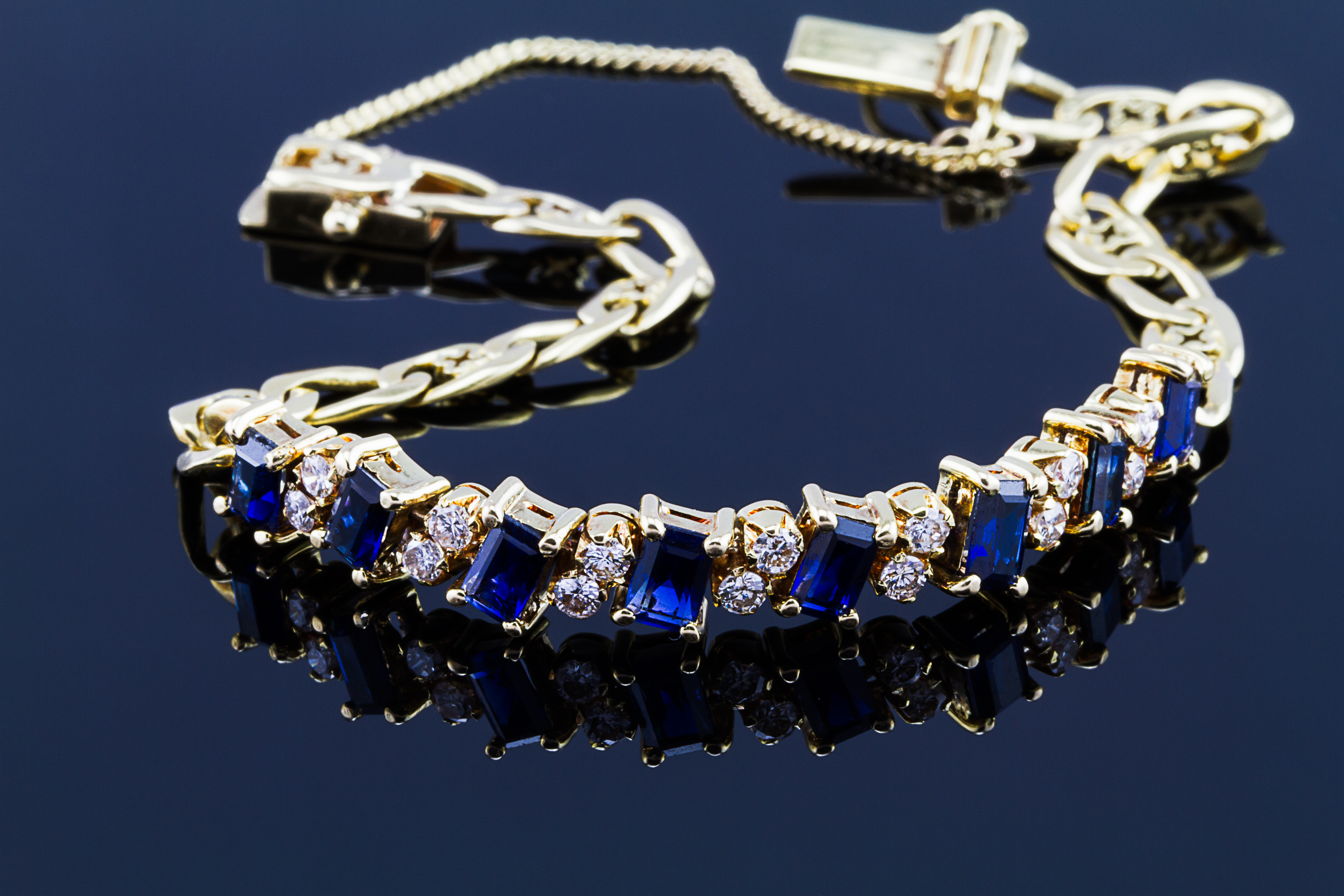 Selective focus of diamond with sapphire bracelet on glossy dark background